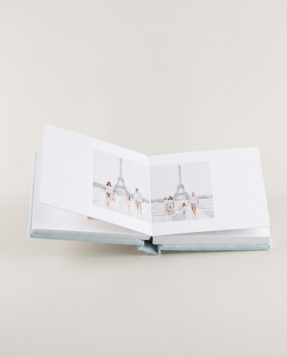 Open album spread with a family portrait at the Eiffel Tower