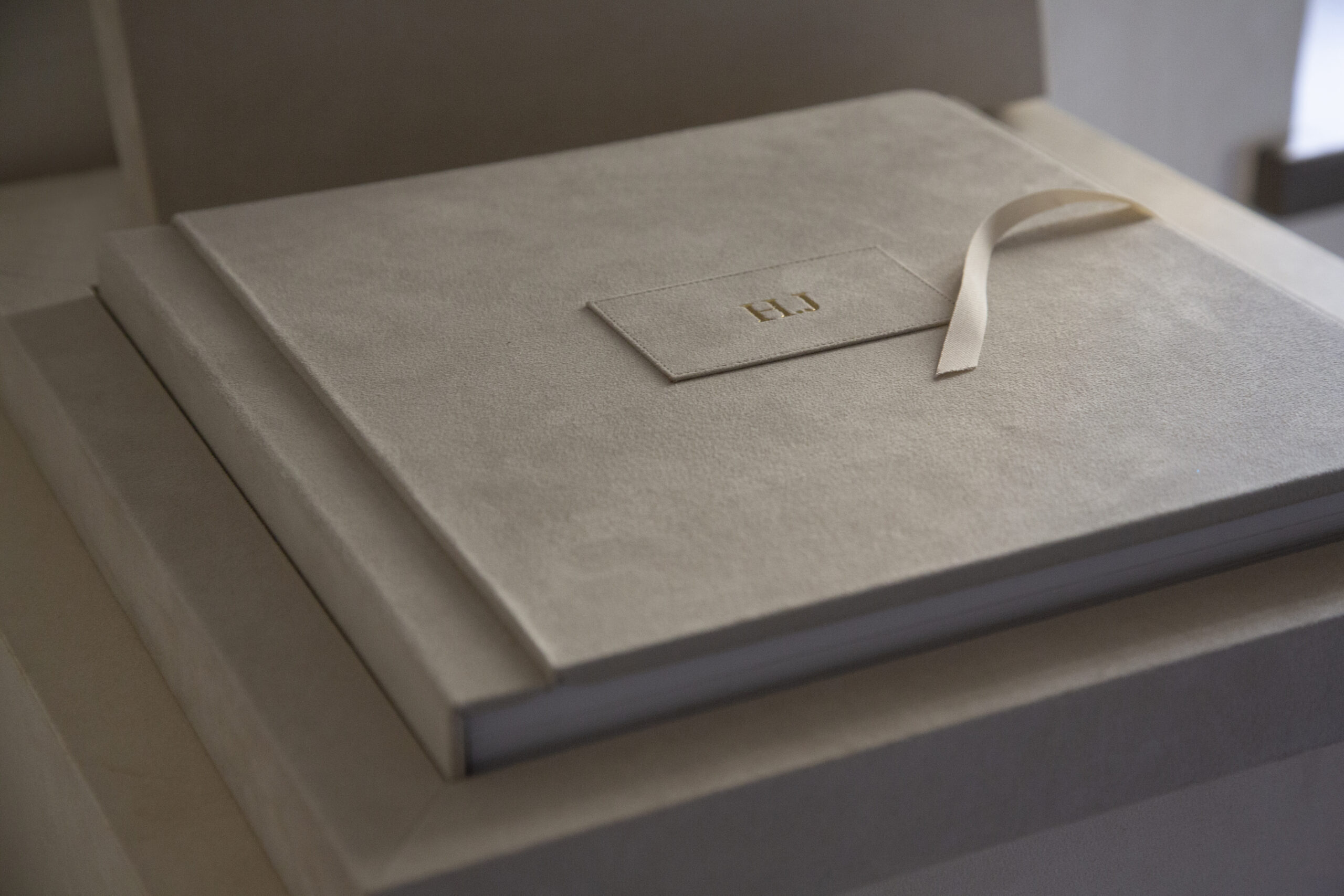 Close view of a Tramontina Collection cover with EL initials, a stitched patch and an ivory ribbon